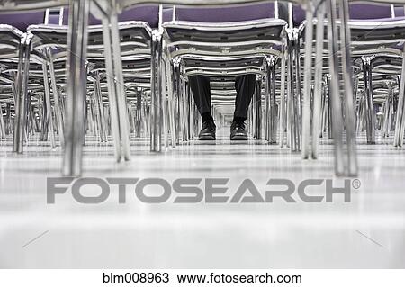 Stock Image - Black businessman waiting in empty conference center. Fotosearch
