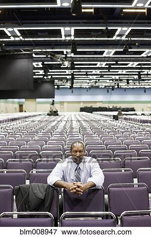 Stock Photo - Black businessman waiting in empty conference room. Fotosearch