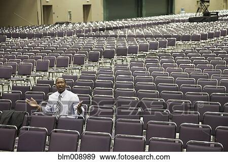 Stock Photo - Black businessman waiting in empty conference center. Fotosearch