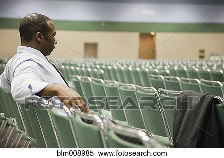 Stock Photography - Black businessman waiting in empty conference center. Fotosearch