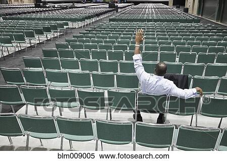 Stock Photography - Black businessman waiting in empty conference center waving. Fotosearch
