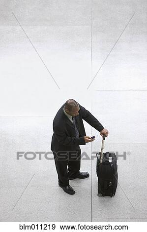 Stock Photo - Black businessman with suitcase using cell phone. Fotosearch