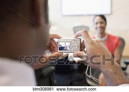 Stock Image - Black businesspeople taking digital photographs in office. Fotosearch
