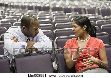 Stock Image - Black businesspeople talking in empty conference center. Fotosearch