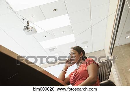 Stock Image - Black businesswoman sitting at conference table. Fotosearch