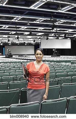 Stock Image - Black businesswoman standing in empty conference center. Fotosearch