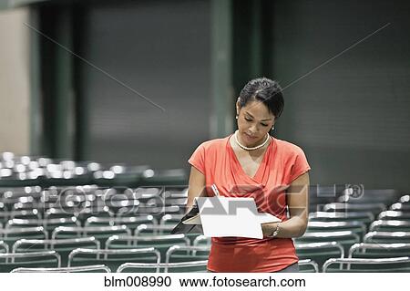 Stock Image - Black businesswoman standing in empty conference center. Fotosearch