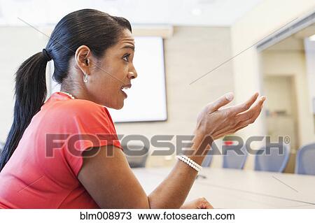 Stock Image - Black businesswoman talking in conference room. Fotosearch