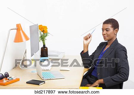 Stock Photo - Black businesswoman using laptop at office desk. Fotosearch