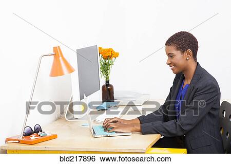 Black businesswoman using laptop at office desk View Large Photo Image Stock Photograph - Black businesswoman using laptop at office desk. Fotosearch