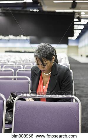 Stock Photograph - Black businesswoman waiting in empty conference center. Fotosearch