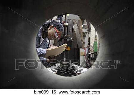 Stock Photograph - Black factory worker as seen through metal pipe. Fotosearch