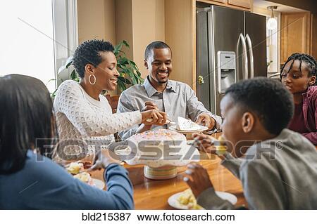Stock Photo - Black family eating cake at birthday party. Fotosearch