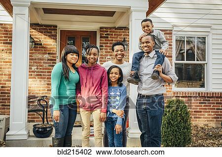Stock Image - Black family smiling outside house. Fotosearch