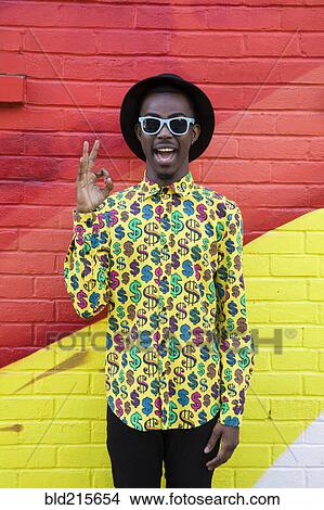 Black man in sunglasses making okay sign near colorful wall View Large Photo Image Picture - Black man in sunglasses making okay sign near colorful wall. Fotosearch