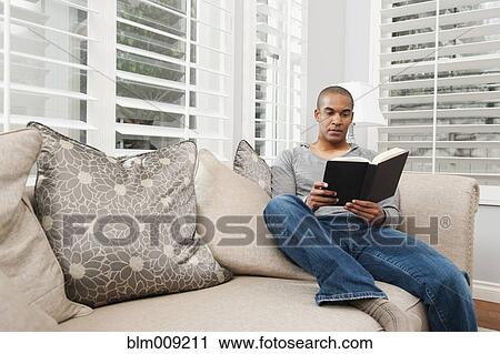Black man reading book on sofa View Large Photo Image Stock Image - Black man reading book on sofa. Fotosearch