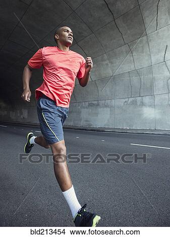 Picture - Black man running in urban tunnel. Fotosearch
