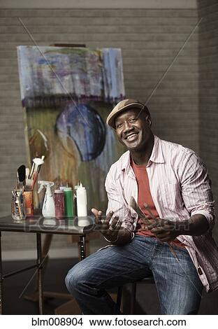 Picture - Black man sitting in artist's studio. Fotosearch