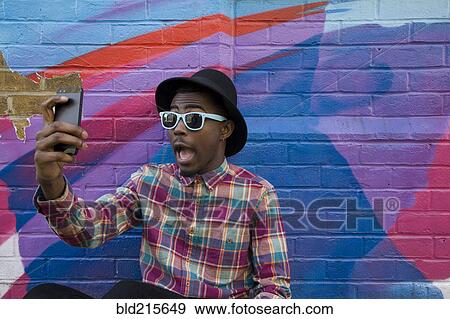 Black man taking selfie near colorful wall View Large Photo Image Stock Photo - Black man taking selfie near colorful wall. Fotosearch
