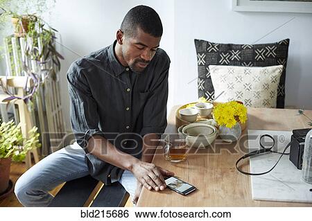 Black man using cell phone at table View Large Photo Image Stock Photograph - Black man using cell phone at table. Fotosearch