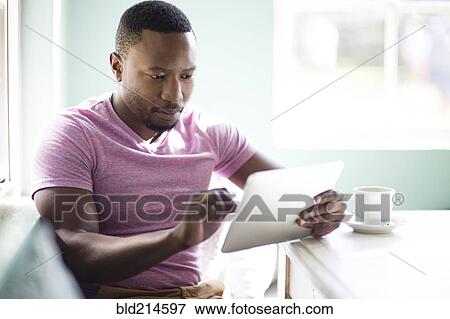 Stock Photo - Black man using digital tablet at breakfast. Fotosearch