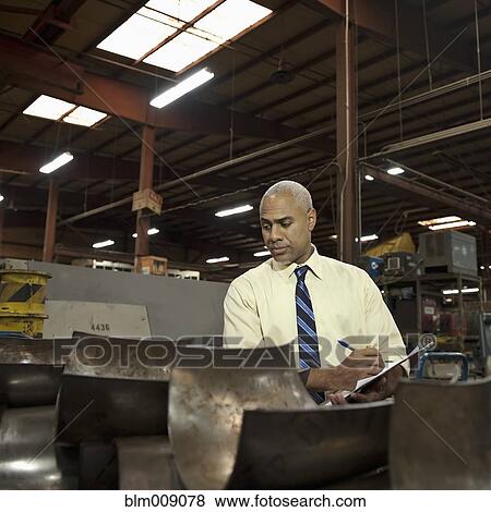 Stock Photo - Black manager examining, metal in factory. Fotosearch