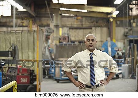 Stock Photograph - Black manager standing in factory. Fotosearch