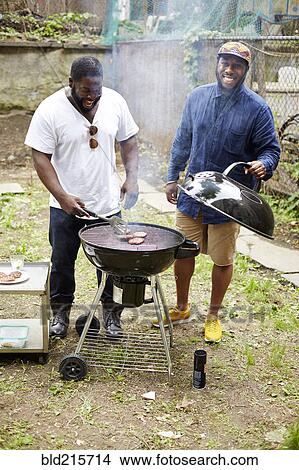 Picture - Black men grilling hamburgers at backyard barbecue. Fotosearch