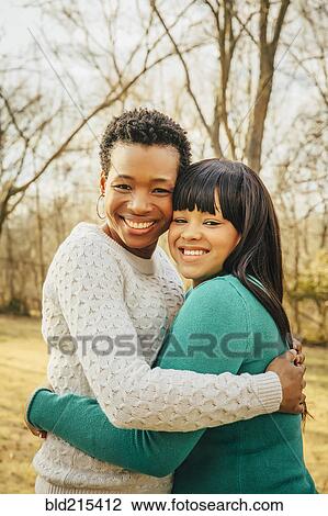 Stock Image - Black mother and daughter hugging outdoors. Fotosearch