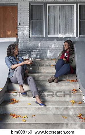 Black mother and daughter sitting on front stoop drinking wine View Large Photo Image Stock Photo - Black mother and daughter sitting on front stoop drinking wine. Fotosearch
