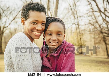 Stock Image - Black mother and daughter smiling outdoors. Fotosearch