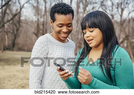 Black mother and daughter using cell phone outdoors View Large Photo Image Stock Image - Black mother and daughter using cell phone outdoors. Fotosearch