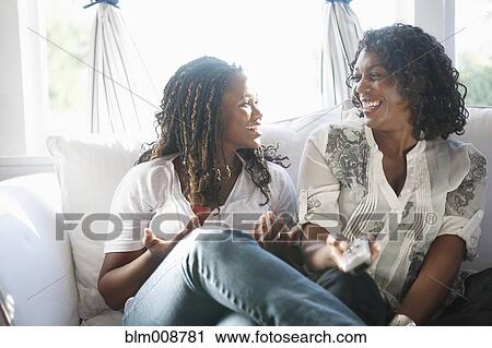 Stock Image - Black mother and daughter watching television together. Fotosearch