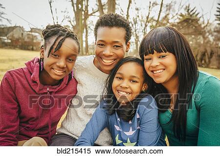 Stock Photography - Black mother and daughters sitting outdoors. Fotosearch