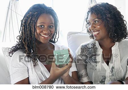 Stock Image - Black mother giving daughter gift. Fotosearch