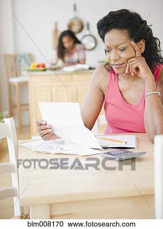 Stock Image - Black mother looking at monthly bills. Fotosearch