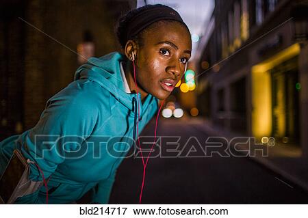 Stock Photo - Black runner resting on city street at night. Fotosearch