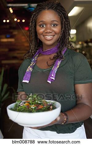 Stock Photo - Black waitress serving salad in restaurant. Fotosearch