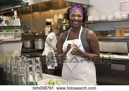 Stock Image - Black waitress working in restaurant kitchen. Fotosearch