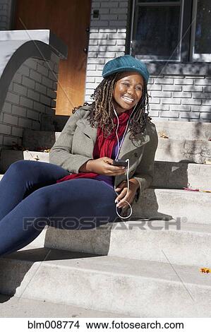 Picture - Black woman listening to music on mp3 player. Fotosearch