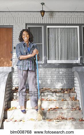 Stock Photo - Black woman sweeping front stoop steps. Fotosearch