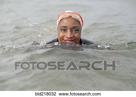 Stock Image - Black woman swimming in ocean. Fotosearch