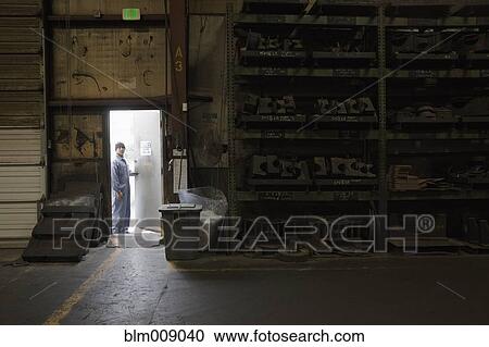 Stock Image - Black worker opening door in factory. Fotosearch
