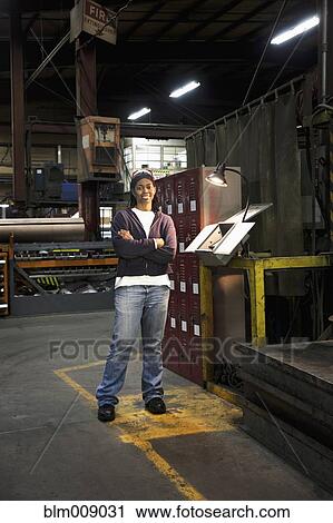 Stock Image - Black worker standing in factory. Fotosearch