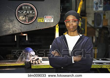 Stock Image - Black worker standing in factory. Fotosearch