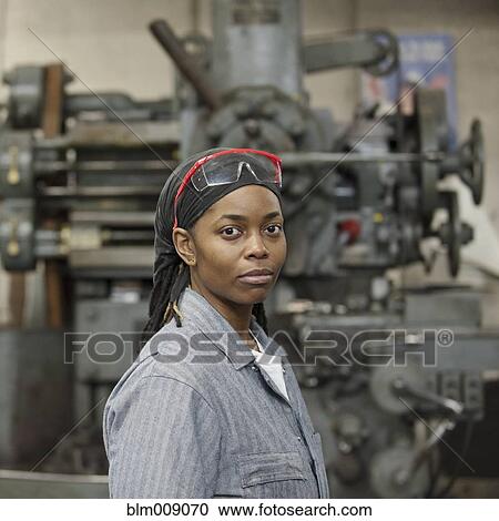 Stock Image - Black worker standing in factory. Fotosearch