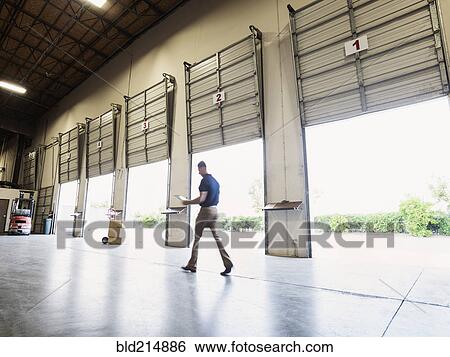 Stock Photograph - Blurred view of Caucasian worker walking in warehouse. Fotosearch