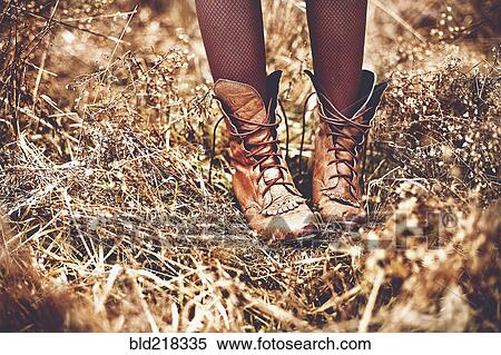 Stock Photography - Boots of Caucasian teenage girl standing in tall grass. Fotosearch