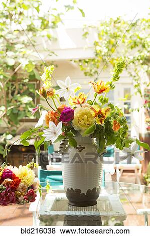 Stock Photo - Bouquet of flowers in vase on backyard patio. Fotosearch