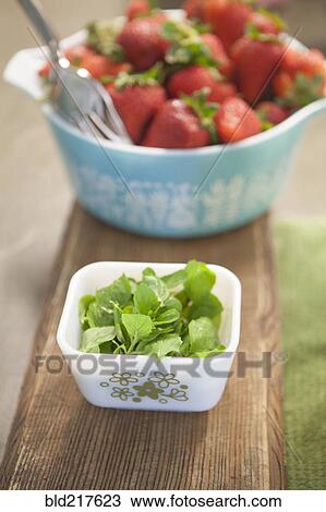 Stock Image - Bowls of fresh herbs and strawberries. Fotosearch